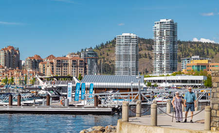 A view of the Kelowna Skyline and Okanagan Lake British Columbia Canada in the summer. Cityscape on sunny summer day. People walking on a Kelowna Boardwalk-Travel photo, copyspace for text-June 7,2022のeditorial素材