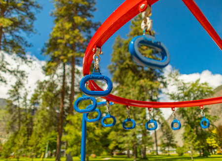 Hanging monkey bars in a summer playground in a city park. Row of blue hanging rings in a park....