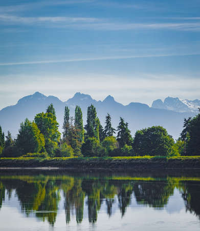 Beautiful scenic landscape view of a river, forest and mountains in the misty morning. The River And...