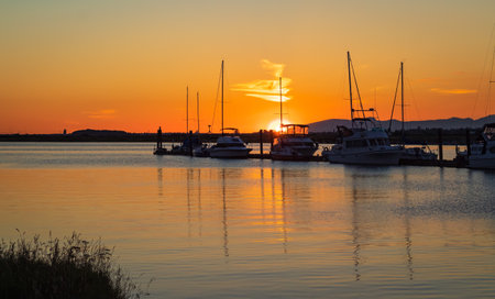 Beautiful sunset at the yacht harbor with pier. Summer sunset at the sea. Leisure time, active life, vacation and holidays concept. Marina with yachts under dark blue sky at sunsetのeditorial素材