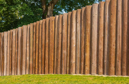 Wooden fence posts, round wood. Wooden wall from logs a strong protection in ancient times. Round...