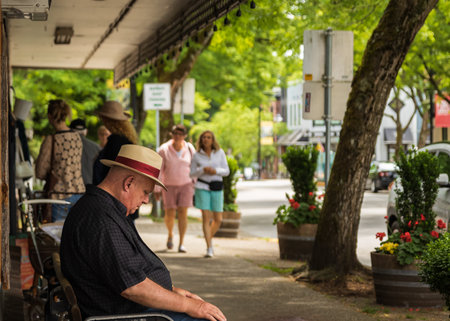 Sad old man sitting on a street bench. Lonely sad miss widower wear hat on city park outside at summer day. Street photo, selective focus-July 5,2022- Langley BC Canada.のeditorial素材