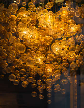 lighting balls on the chandelier in the lamplight, light bulbs hanging from the ceiling, lamps on the dark background. Selective focus, horizontal, nobodyの写真素材