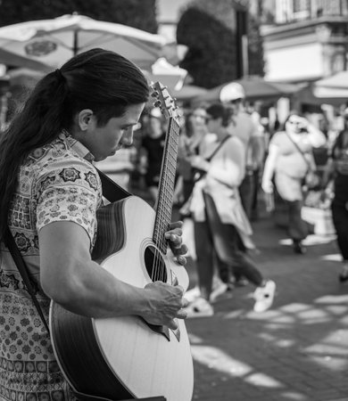 A romantic man is playing the guitar on the city street. A street musician plays outdoor. Love, romance, lovers, serenade, romance, travel photo-July 19,2022-Victoria BC Canadaのeditorial素材