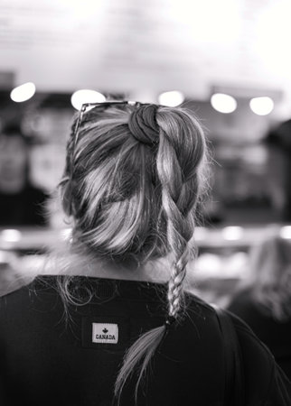 Rear view of a beautiful woman with elegant elaborate hairstyle. Blonde tourist girl with braid photo in black and white. Street photo, rtavel photo, selective focusの写真素材