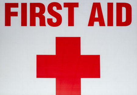 Red First Aid sign mounted to wall on white background. Street photo, nobodyの写真素材