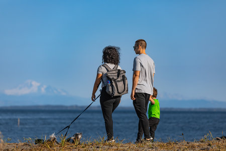 Happy young family spending time together outside in nature by the sea. Active family with dog walking in the park. Travel photo, copyspace for text-October 18,2022-Surrey BC Canadaのeditorial素材