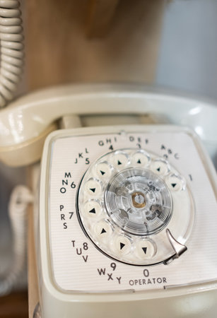 vintage telephone. White 60s rotary dial phone. Antique vintage analog telephone dialing or scrolling phone on a table. Nobody, blurred, selective focusの写真素材