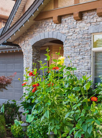 Entrance of a luxury house with a patio and beautiful landscaping on a sunny day. Garden in front of detached houseの写真素材