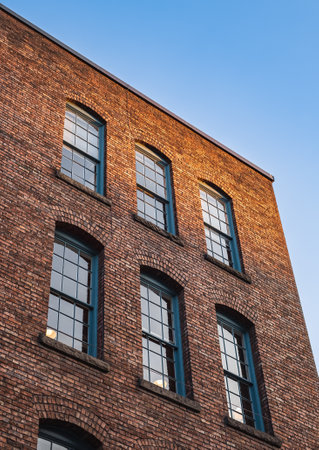 Many equal windows of the factory. Old red brick building or factory with many windows. Street photo, nobodyの写真素材