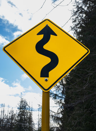 road sign. Warning winding traffic sign winding road on background. Yellow winding road sign....