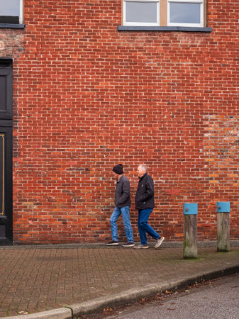 Men walking fast on the brick wall background in old town. Urban infrastructure, people walking fast...