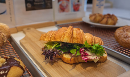 Vegetarian croissant on a wooden board. Croissant sandwich with vegetables, close-up. Healthy breakfast concept.の写真素材
