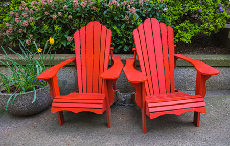 Red Adirondack chair setting at the garden. Traditional curveback red wooden beach chair, outdoor...