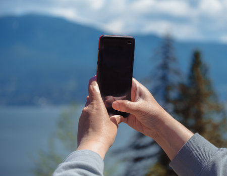 A woman holding phone showing Black screen. Close up of women's hands holding cell telephone taking photos or videos of a nature. Blank copy space screen for your advertising text. Smartphone on handの写真素材