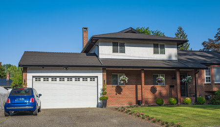 Real Estate Exterior Front House on a sunny day. Big custom made luxury house with nicely landscaped front yard and driveway to garage in summer in the suburbs. Beautiful house entrance with a gardenの写真素材