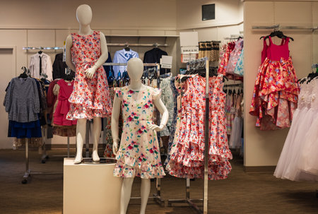 Children mannequins standing in shop. Dressed mannequins in romantic classic dresses. fashion for girls. Clothes On Shelves And Hanger In Store Of Shopping Center. Nobody, selective focusの写真素材