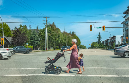 Active senior grandmother holding hand of her granddaughter while crossing street. grandmother with...