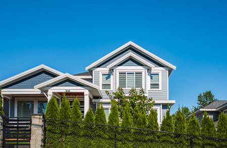 Real Estate Exterior Front House on a sunny day. Big custom made luxury house with nicely landscaped front yard in summer in the suburbs. Beautiful house entrance with a garden with colorful flowers