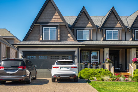 Real Estate Exterior Front House on a sunny day. Big custom made luxury houses with nicely landscaped front yard and driveway to garage in summer in the suburbs. Beautiful house entrance with a gardenの写真素材