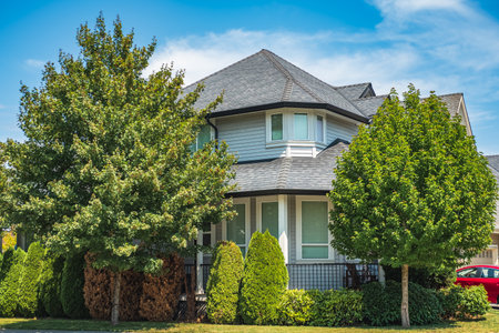 Real Estate Exterior Front House on a sunny day. Big custom made luxury house with nicely landscaped front yard in summer in the suburbs. Beautiful house entrance with a garden with colorful flowers