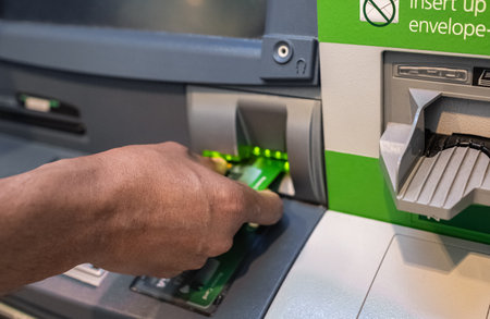 Man's hand inserting a credit card in ATM , Hand inserting ATM plastic card into bank machine to withdraw money, finance money bank concept. ATM credit card into bank machine to withdraw moneyの写真素材