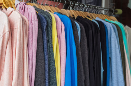 Multicolored hoodie hang on hangers in the store. Row of different colorful youth cashmere sweaters and hoodies, sweatshirts on a clothes rack. Hoodies on hangers in a clothing storeの写真素材