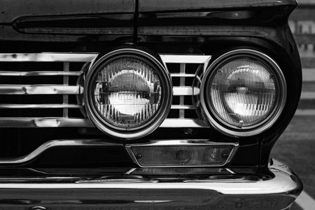 Classic car headlights close-up. Headlights of black vintage car. Black classic car concept. Details of the front side luxury car, photo in black and white. Street photo, nobodyの写真素材