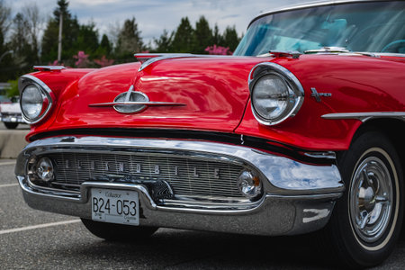 Frontal photo of a classic luxury red car. Color detail on the headlight of a vintage car. Front of an old American car on a street of Vancouver Canada-April 30,2023のeditorial素材