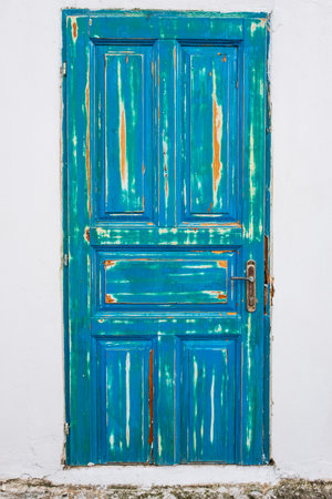 Turquoise old wooden door over white wall. Retro style wooden door on white cement wall background. Nobody, street photoの写真素材