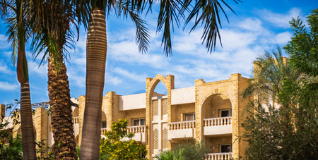 Villas compound development in a bright sunny day with white clouds in the blue sky. Living house with apartments and balconies in arabian style. Nobody, street photoの写真素材