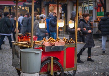 Man, Street vendor selling roasted corns and chestnuts in a crowded street of Eminonu district, corn and chestnut is popular snack in Istanbul city. Istanbul, Turkey-December 20,2023のeditorial素材