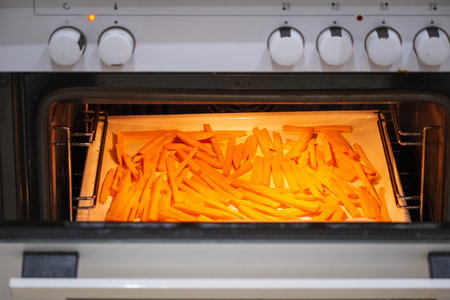 A tray of oven baked sweet potato chips in closeup. Sliced sweet potato in the the oven. Roasted sweet potato. Vegetarian Oven baked sweet potatoの写真素材