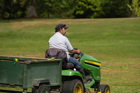 A mature farmer driving mini tractor John Deere X 380 outdoor. Work on agricultural machinery on the field. Vancouver Canada-August 30,2023-Editorialのeditorial素材