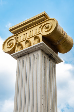 Top part of pillar, Greek-style columns with golden top, exterior detail. Greek-style columns with golden tops against blue sky. Travel photo, nobodyの写真素材
