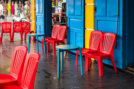 Colorful chairs and small tables in a street side cafe are inviting people to sit down. Cafe summer...