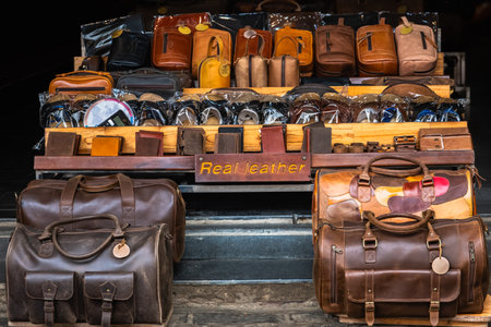 Shelf with fashion bags in a store. Close up of different leather bags on market. Modern colorful bags for sale. Leather accessories purses, handbags displayed at store in traditional street marketの写真素材