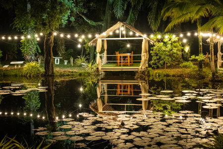 Pergola with glowing lights by the water. Gazebo with lights by the lake in late evening. Romantic scene in dusk. Patio romantic in the evening. Night gazebo, pavilion garden at nightの写真素材