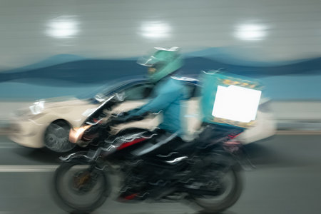 Motorcycle driver delivers food delivery, blurred effect. Abstract long exposure photo. Deliver food man on motorbike making his way through busy streets. Delivery service man ride a Motorcycleの写真素材