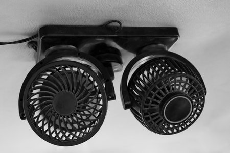 Portable fan on the ceiling in a car. Summer heat. Dual-head car cooling fan. USB car fan. 360 degree rotating fan for vehicle. Nobody, close up, selective focusの写真素材