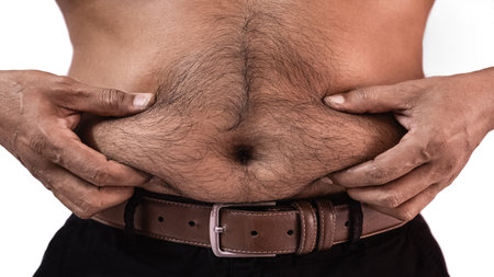 Man assessing his belly fat problem. Overweight man standing and show his tummy on white background. Fat people and Obesity concept. Men at risk for diabetes Belly fat. Man pinching his belly fatの写真素材