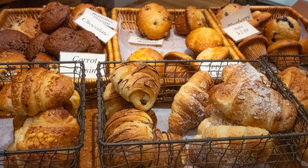 Bistro showcase with shelves of freshly croissants. Assorted pastry arranged on tray selling in a bakery shop. Close up of appetizing golden croissants in cafe shop window. Fresh croissants on a shelfの写真素材