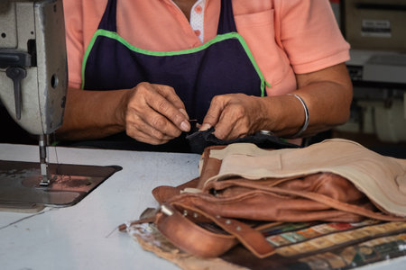 Asian woman textile worker using sewing machine on production line. Senior rural woman working as a tailor using sewing machine stitching clothes Phuket Thailand. Asian manufactureの写真素材