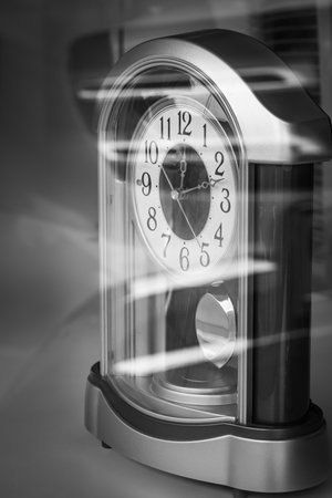 Vintage table clock without alarm on a table. View through the window Antique Clock, retro style, copy space. Ten pass twelve on a clock's. Nobody, selective focusの写真素材
