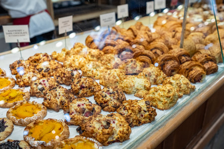 Showcase with different tasty desserts in bakery shop, closeup. Various types of bread and pastry, croissants, cookies on display in a bakery . Modern bakery with different kinds of baked goodsの写真素材