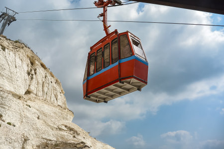 One cable car going up blue sky and white clouds on background. The cable car for tourists, skiers...