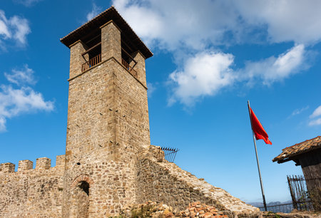 Historical architecture of Preza Fortress Albania. Clock Tower of Preze Castle, Tirana with albanian flag on blue sky background. Tourism travel conceptの写真素材