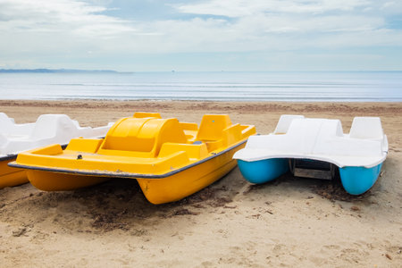 Colorful pedalos on a beautiful tropical beach. Pedal boats parked on the beach with blue sky. Colorful pedal boats. Travel photo, copy space, nobody.の写真素材