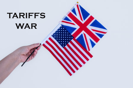 Economic Tariffs Concept. America tariffs on UK. Crisis, Trade and economic war. Flags of United States of America and national flag of United Kingdom with words Tariffs war on white backgroundの写真素材
