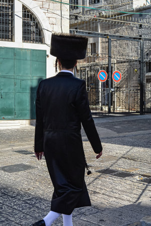 Ultra orthodox Jew with traditional clothes walking in an old city of Jerusalem. Rear view of Hassidic man wearing fur hats shtreimel walking on a street of Jerusalem Israel. Travel photo, selective focusの写真素材